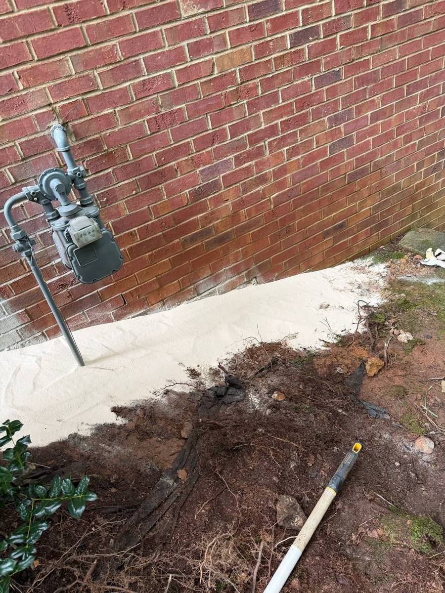 Finished foundation repair along the brick wall near the gas meter, backfilled and leveled