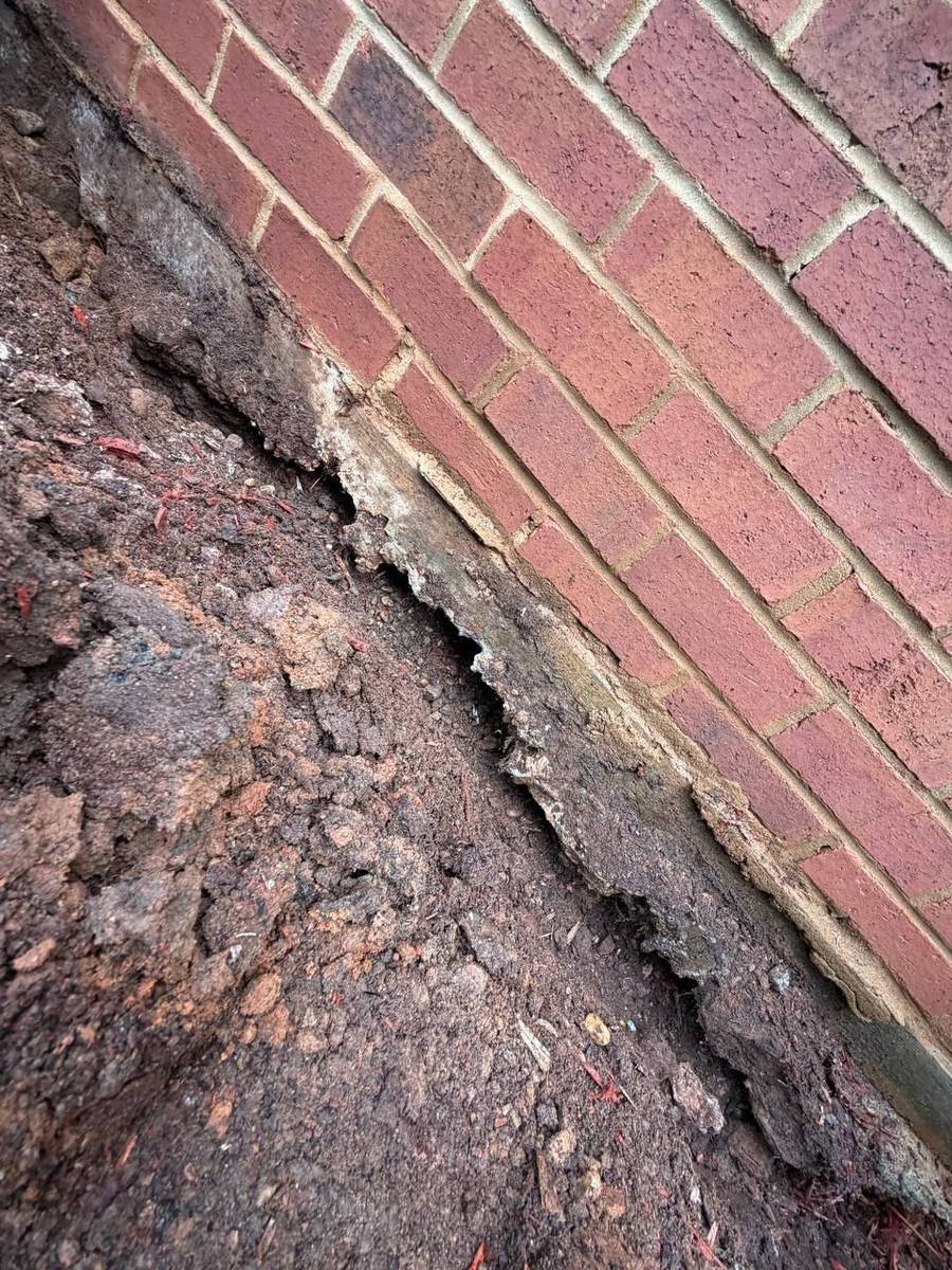 Cracked mortar joint along the brick foundation caused by soil settlement