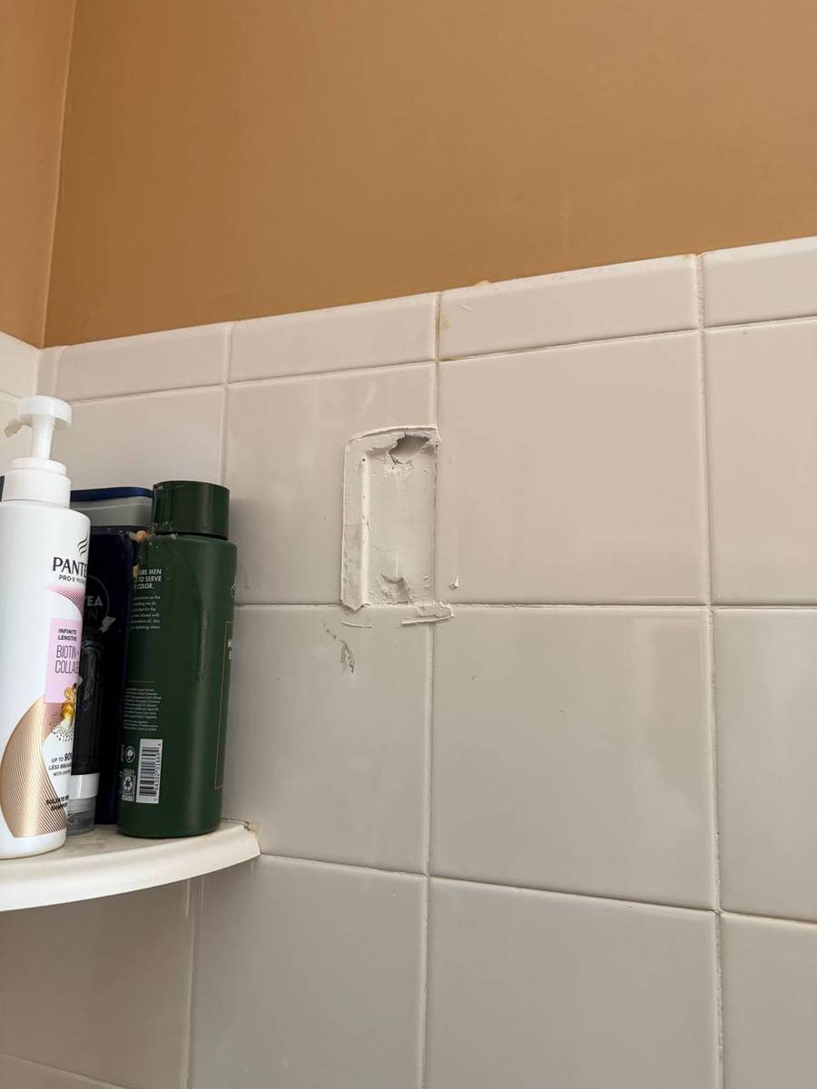 Bare tile spot where a ceramic towel bar holder had come loose and fallen off